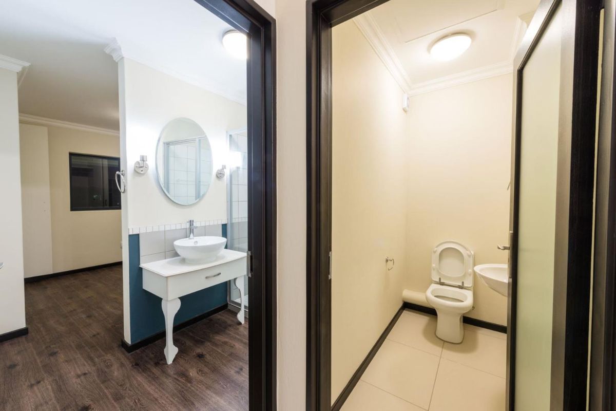 A view into a bathroom featuring a vanity with a vessel sink and a separate enclosed toilet area with tiled flooring.