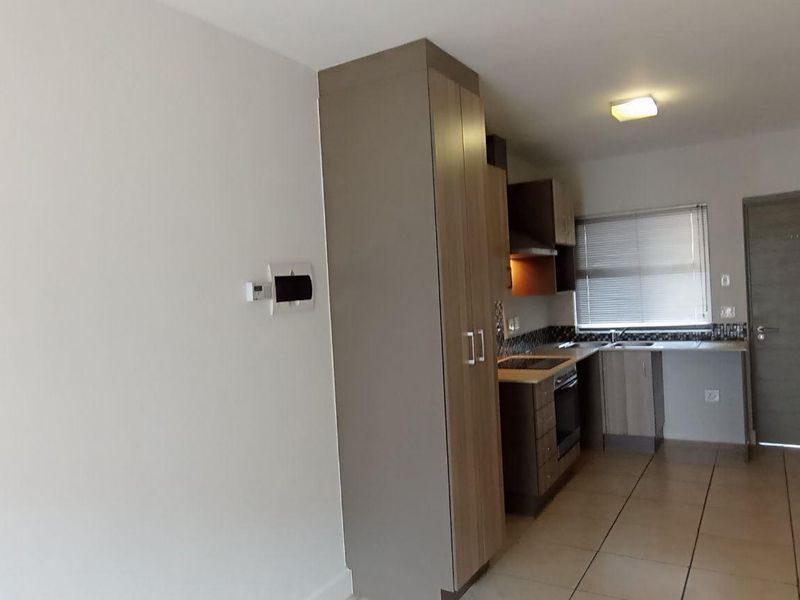 Open plan kitchen area featuring modern built-in cabinetry, integrated oven, extractor fan, and tiled flooring in a well-maintained apartment setting.