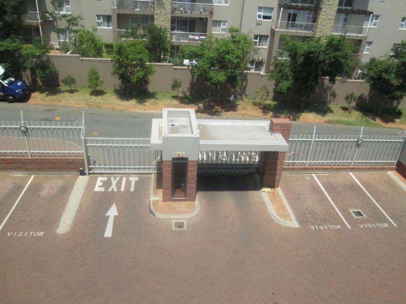An elevated view of the apartment complex security gatehouse, featuring controlled access points and designated visitor parking bays.