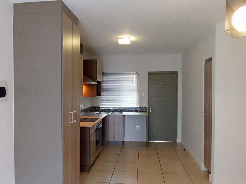 A clean, functional kitchen featuring built-in cabinetry, integrated oven and hob, tiled flooring, and neutral finishes, offering a practical and well-maintained workspace.