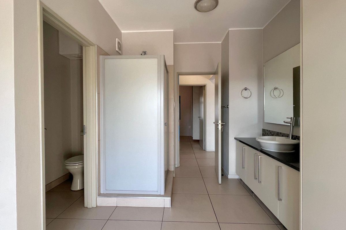 A clean, functional bathroom featuring a vanity with a vessel sink, a separate shower enclosure, and a private toilet area with neutral tile flooring.