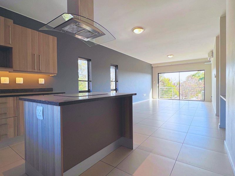 Spacious open-plan living area featuring a modern kitchen with stone countertops, sleek cabinetry, and direct access to a private balcony.