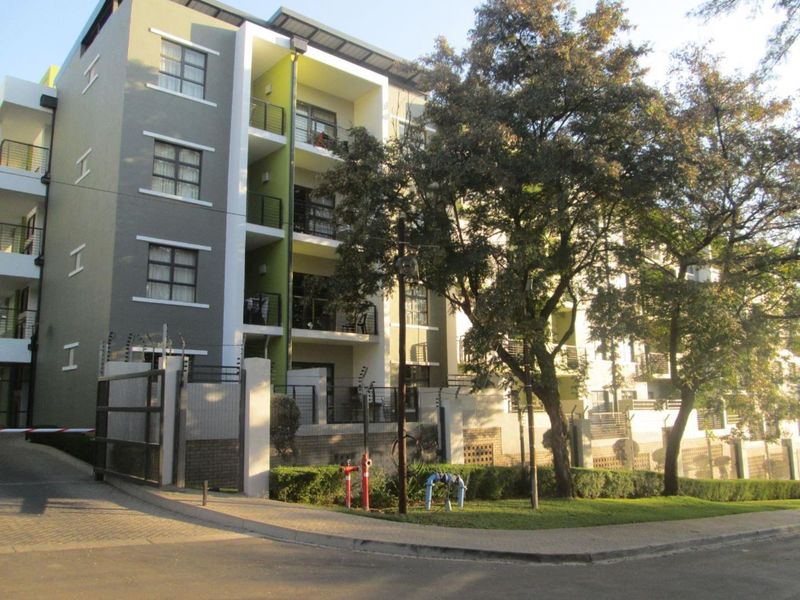 Exterior view of a modern multi-story apartment complex featuring balconies, secure gated access, and landscaped grounds.