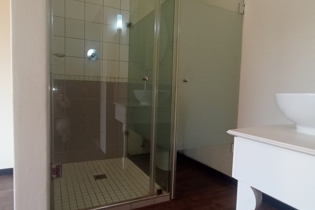 A clean, modern bathroom featuring a glass-enclosed shower with tiled walls and a contemporary vessel sink set on a white vanity cabinet.