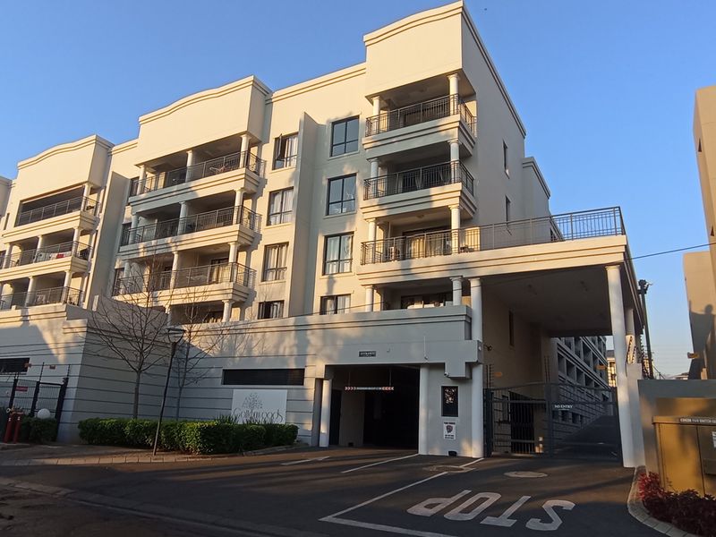 Exterior view of a modern multi-story apartment complex featuring secure gated access, undercover parking, and private balconies for each unit.