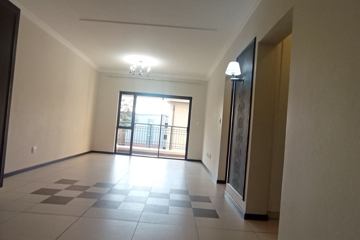 An open-plan living area featuring tiled floors with a decorative pattern, built-in storage, and a sliding glass door leading to an outdoor space.