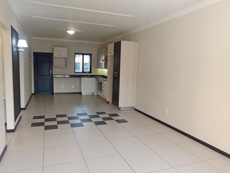 Spacious open-plan living area featuring tiled floors and a functional kitchen with built-in cabinetry, oven, and hob.