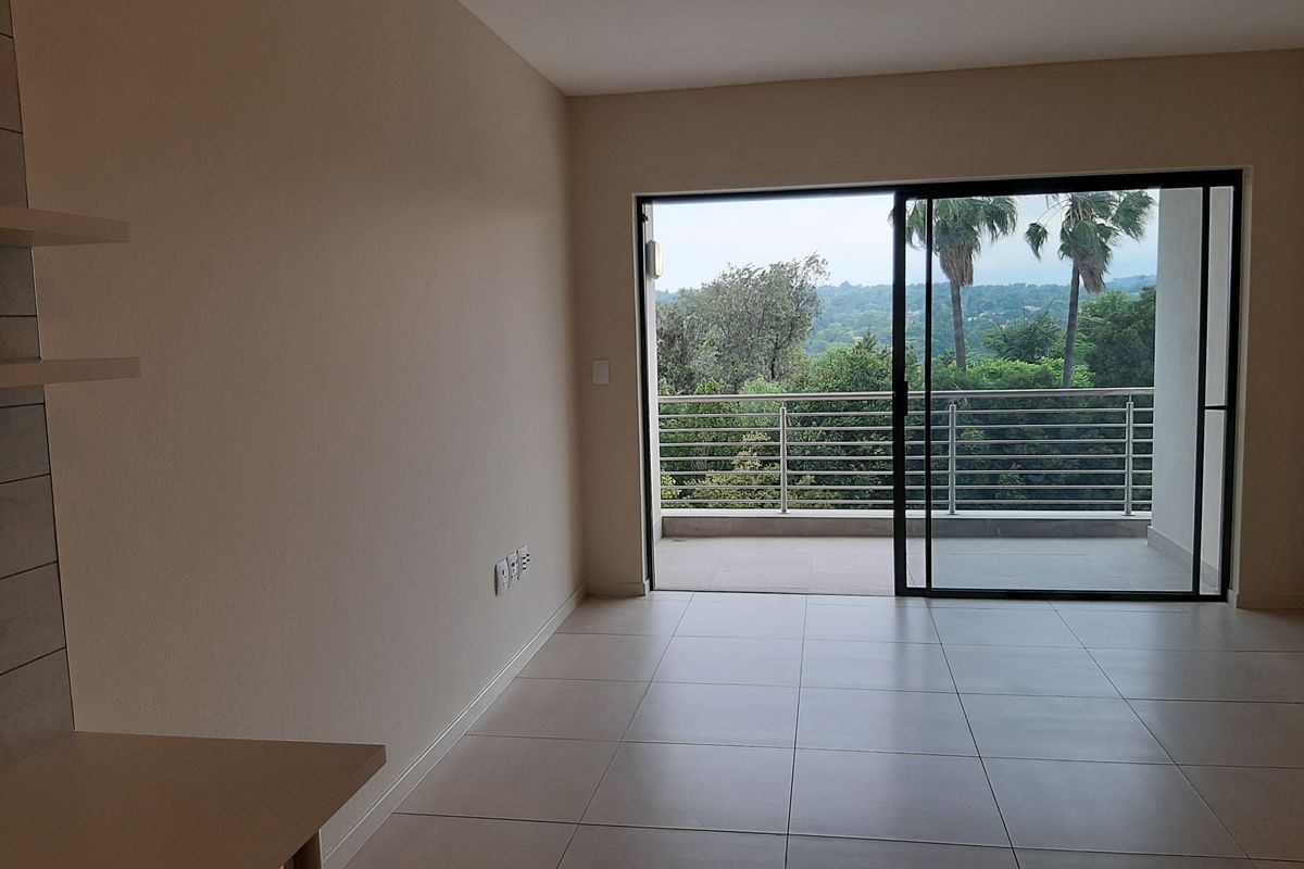 Bright living area featuring large sliding glass doors that open onto a private balcony with scenic treetop views.