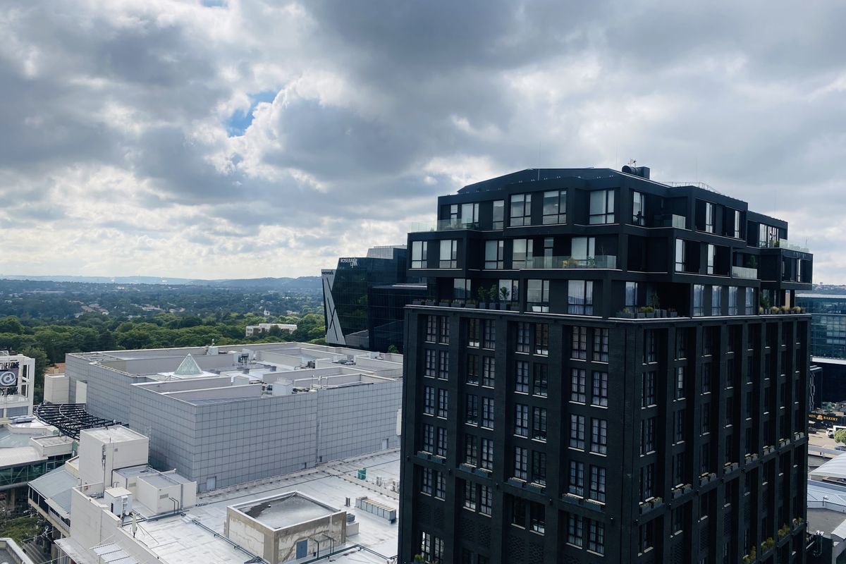 An elevated aerial view showcasing the surrounding urban landscape, featuring modern high-rise architecture and commercial buildings under a cloudy sky.