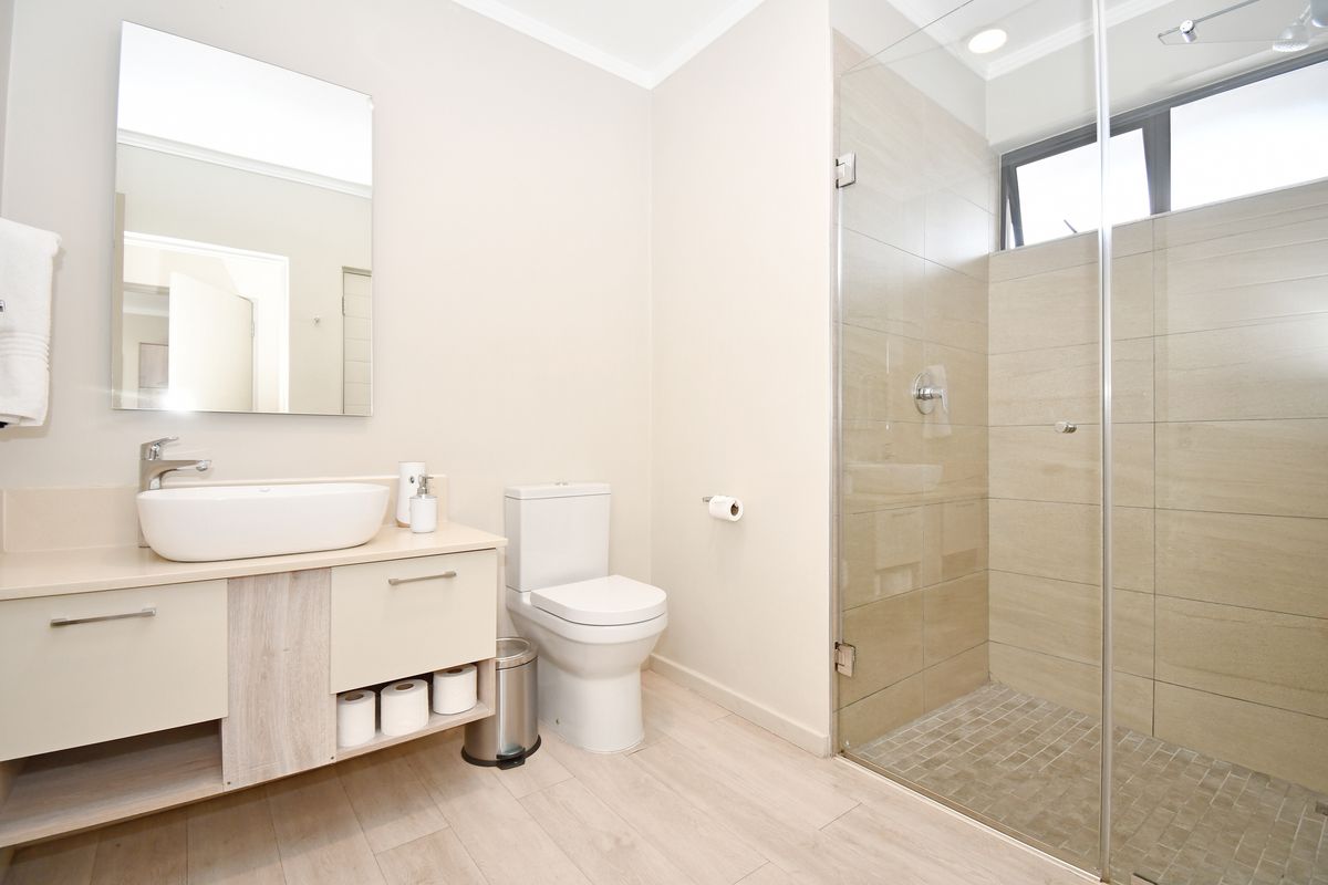 Modern bathroom featuring a floating vanity with vessel sink, a glass-enclosed walk-in shower with tiled walls, and a contemporary toilet.