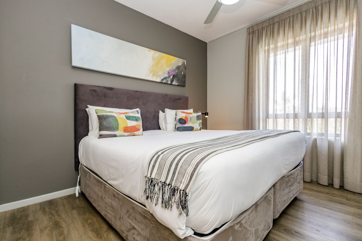A well-maintained bedroom featuring modern wood-look flooring, neutral wall tones, and a ceiling fan, offering a comfortable and inviting living space.
