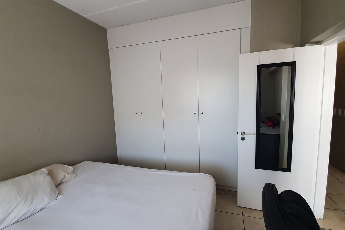 A bedroom featuring built-in white cupboards and tiled flooring, providing functional storage space.
