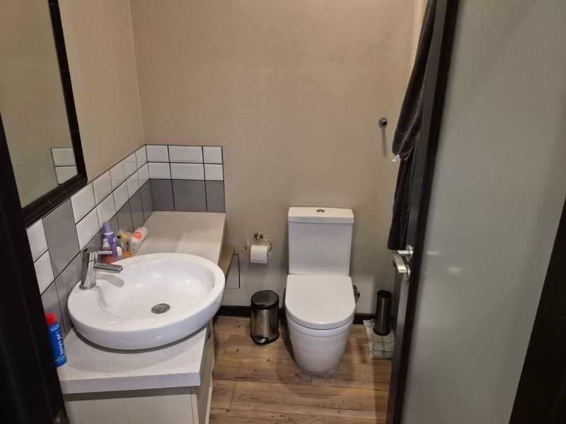 A compact bathroom featuring a modern vessel sink on a vanity countertop, a white toilet, and neutral wall tones with tiled splashback.