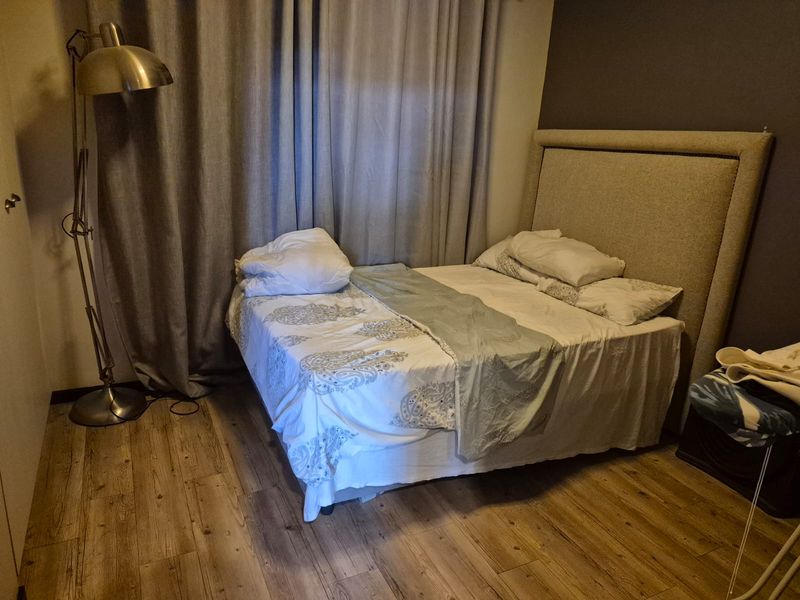 A bedroom featuring laminate flooring and neutral wall tones, providing a functional space for rest.