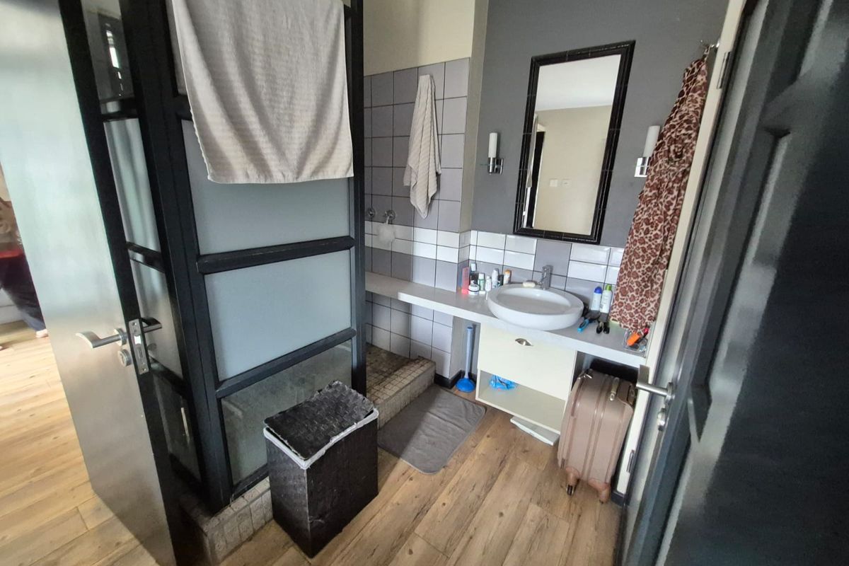 A functional bathroom featuring a vanity basin, tiled splashback, and a separate shower enclosure with a modern black-framed glass partition.