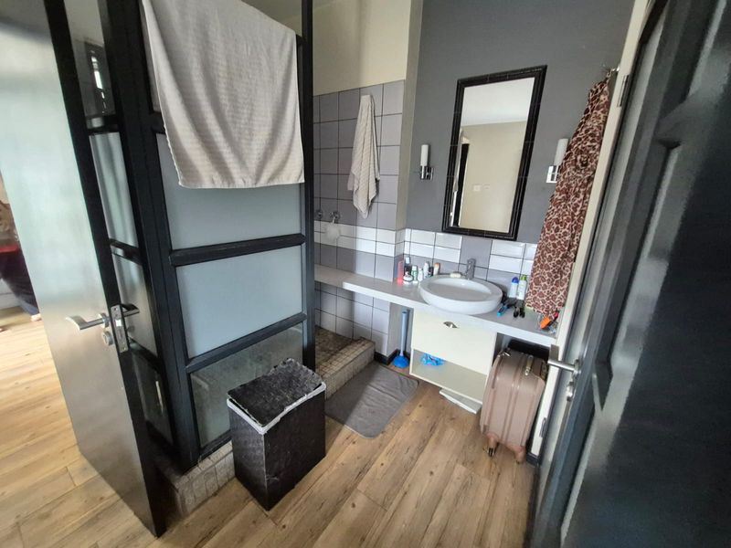 A functional bathroom featuring a vanity basin, tiled splashback, and a separate shower enclosure with a modern black-framed glass partition.