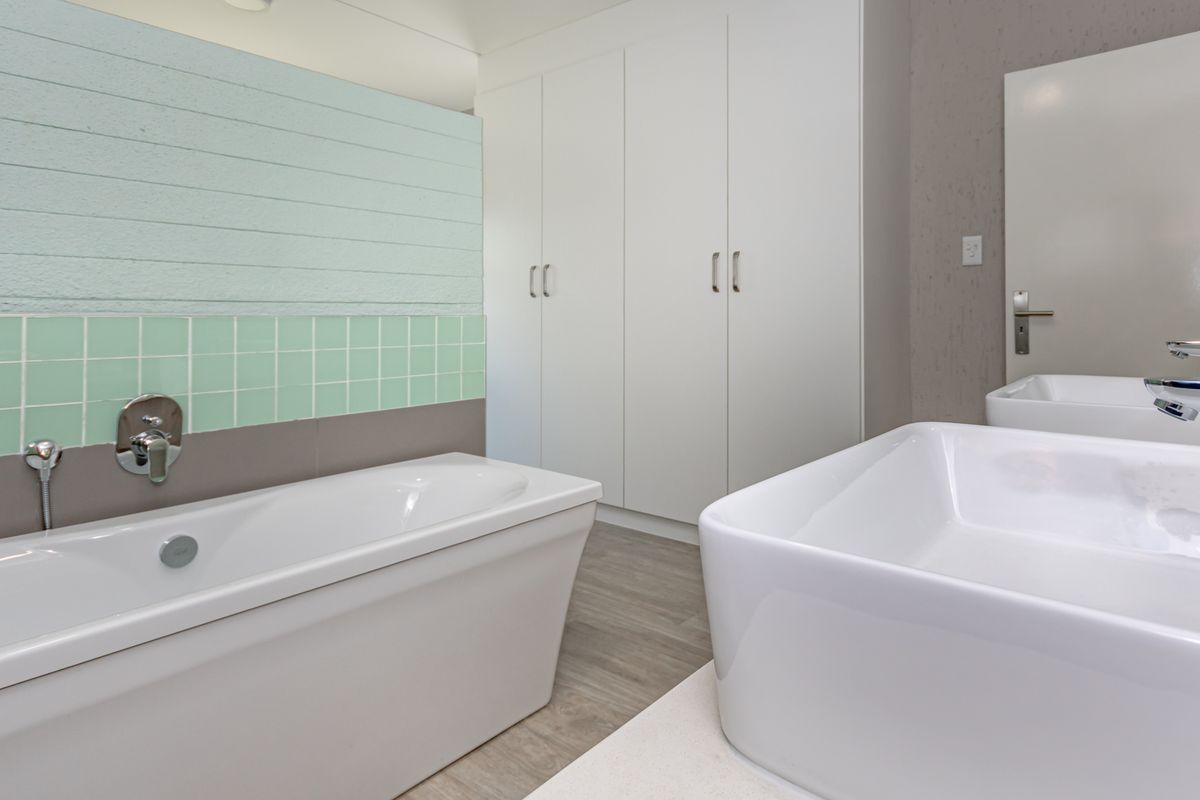Modern bathroom featuring a freestanding bathtub, double vanity with vessel sinks, and ample built-in storage cabinetry.