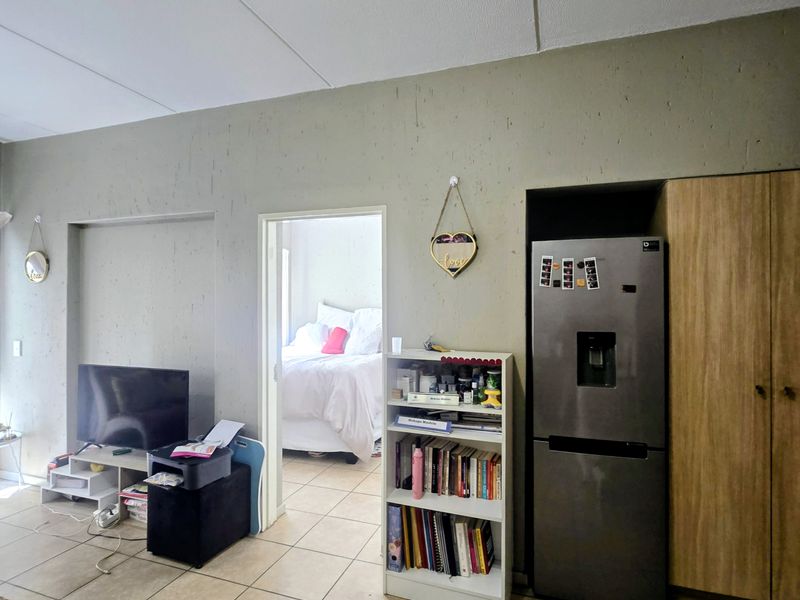A view of the living area featuring tiled flooring and built-in cabinetry, with a doorway leading into an adjacent bedroom.