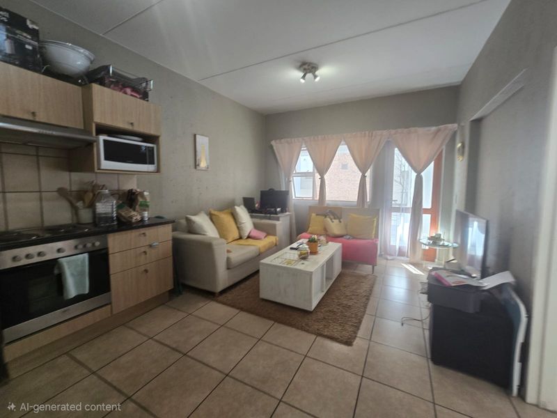 Open-plan living area featuring a compact kitchen with built-in oven and hob, tiled flooring, and direct access to a balcony.