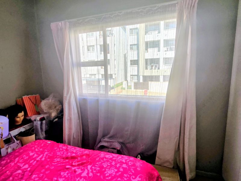 A bedroom featuring tiled flooring and a large window providing natural light and an urban view.