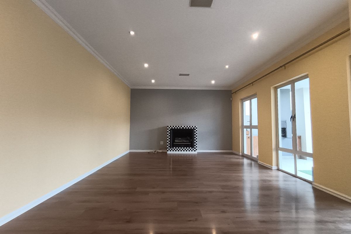 Spacious living room featuring laminate flooring, recessed downlights, a built-in fireplace with a decorative surround, and large sliding glass doors providing natural light.