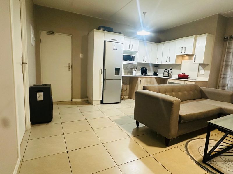 Open-plan living area featuring a functional kitchen with built-in cabinetry and tiled flooring throughout, creating a cohesive and practical living space.