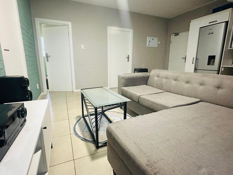 Open plan living area featuring tiled flooring and a compact kitchen section with built-in cabinetry and integrated microwave.