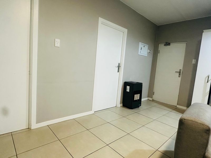 A neutral living area featuring tiled flooring and multiple internal access doors, providing a functional and clean base for interior design.