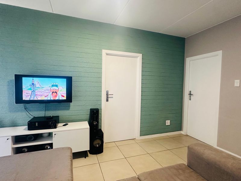 Living room featuring tiled flooring and a distinctive green textured feature wall with two internal doors.