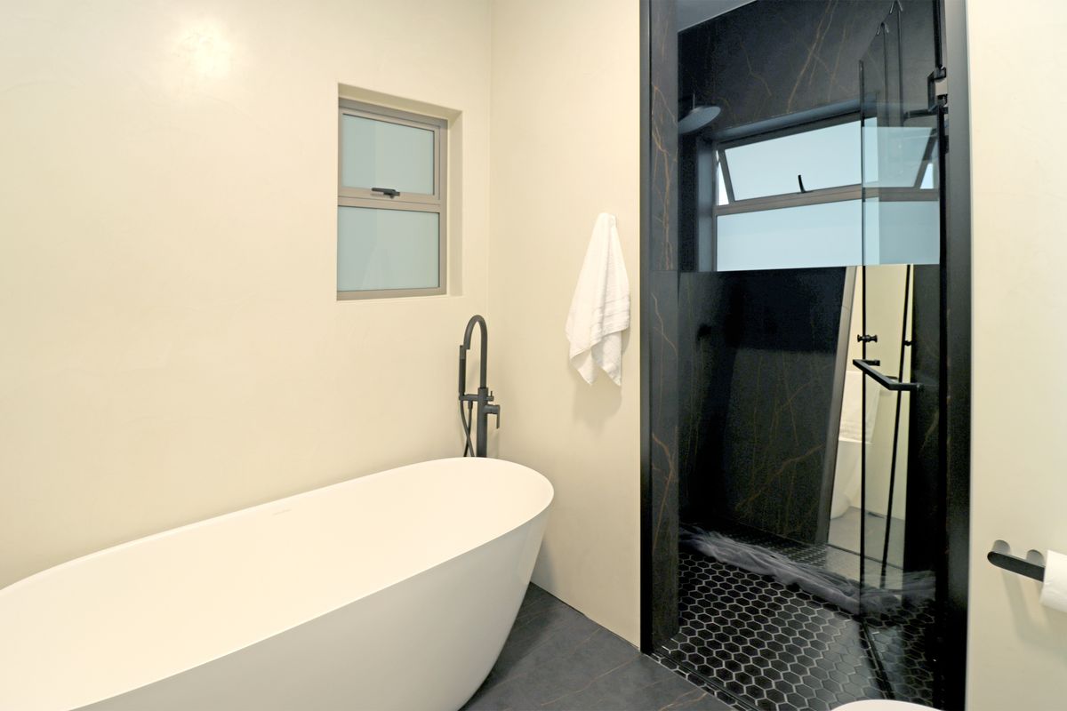 Modern bathroom featuring a freestanding bathtub, a separate walk-in shower with dark marble-effect tiling, and contemporary matte black fixtures.