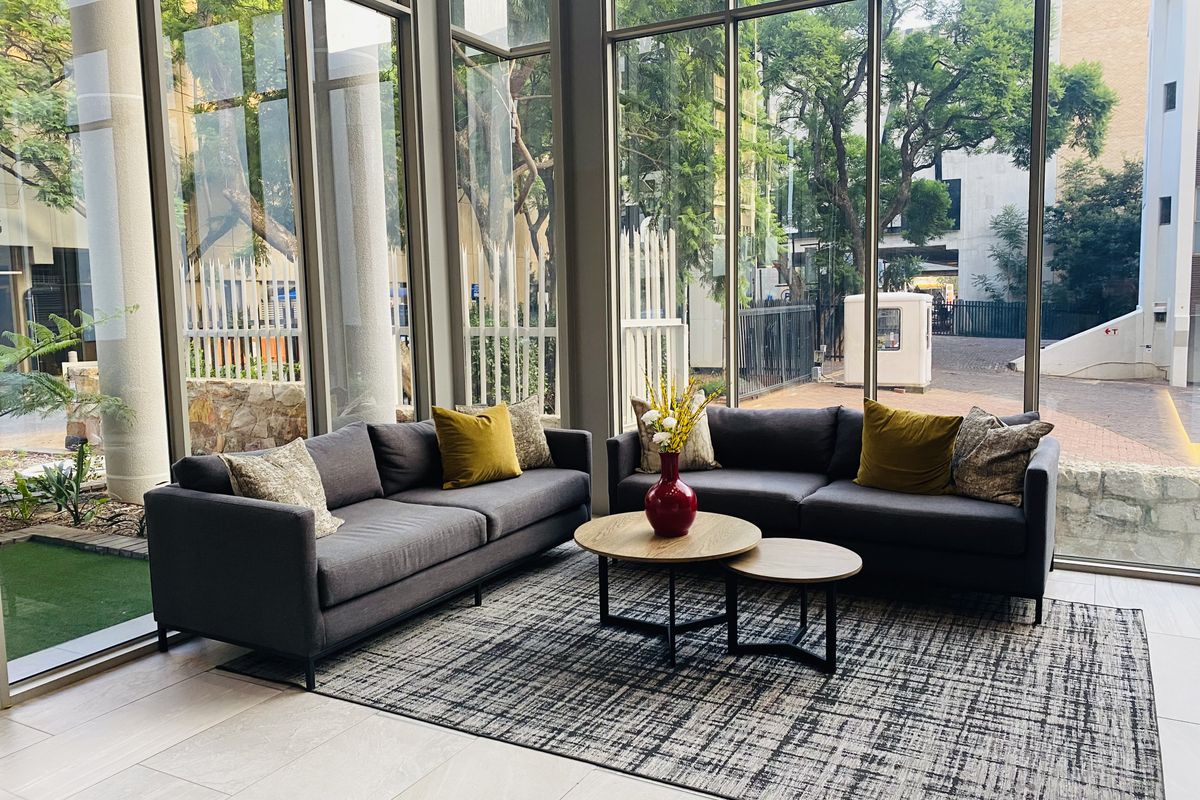 A bright living area featuring floor-to-ceiling glass windows that provide abundant natural light and views of the surrounding greenery.
