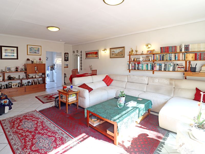 Spacious open-plan living area featuring tiled flooring, wall-mounted shelving, and integrated lighting, providing a versatile layout for lounge and dining arrangements.