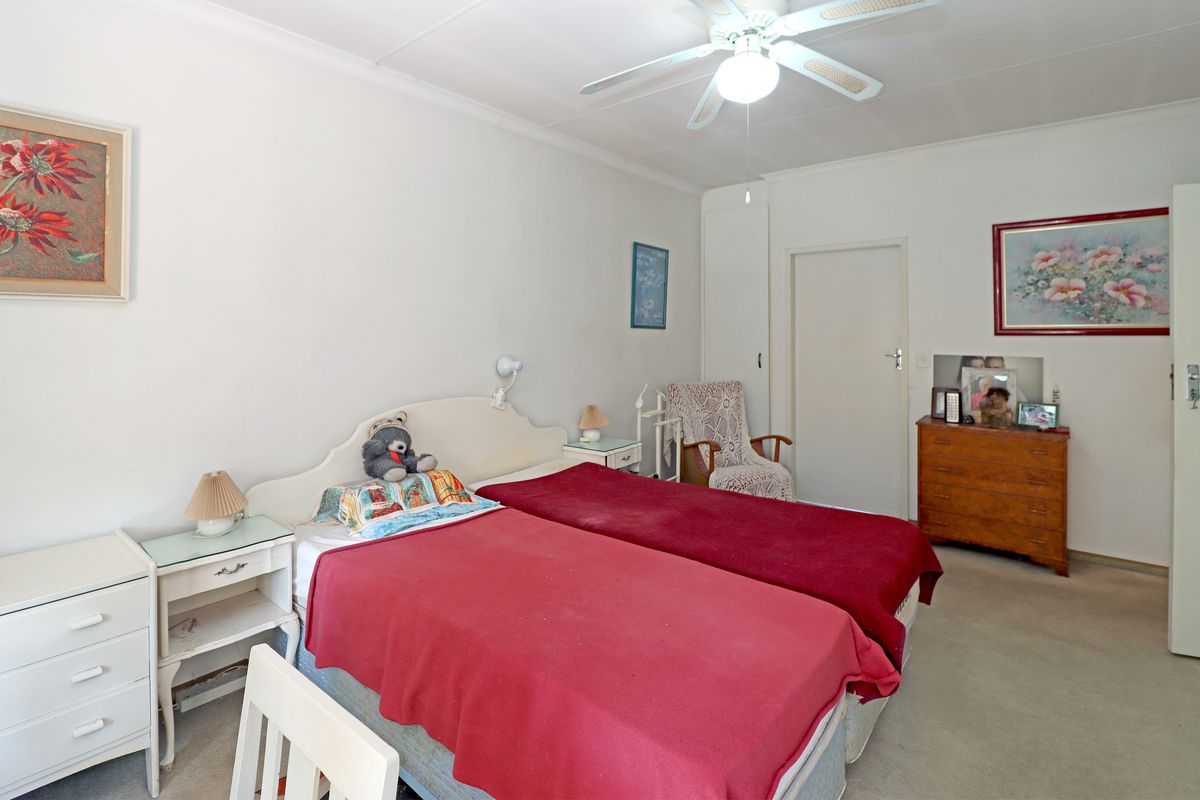A functional bedroom featuring a ceiling fan, built-in storage, and neutral carpeting, offering a comfortable and practical living space.