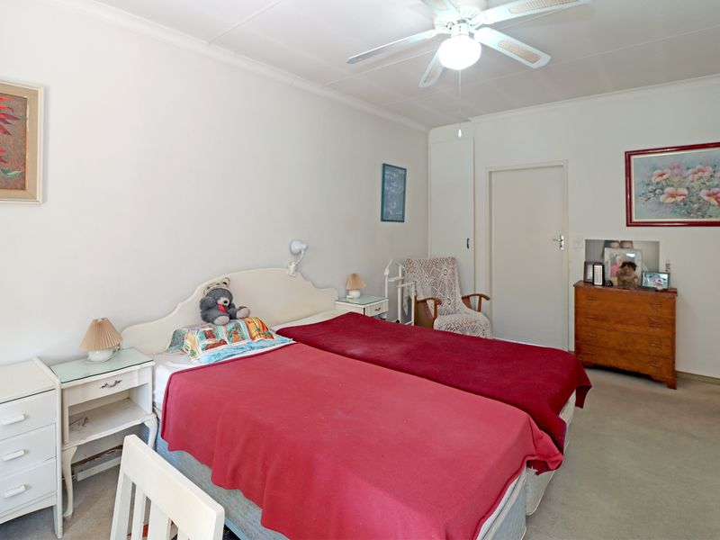 A functional bedroom featuring a ceiling fan, built-in storage, and neutral carpeting, offering a comfortable and practical living space.
