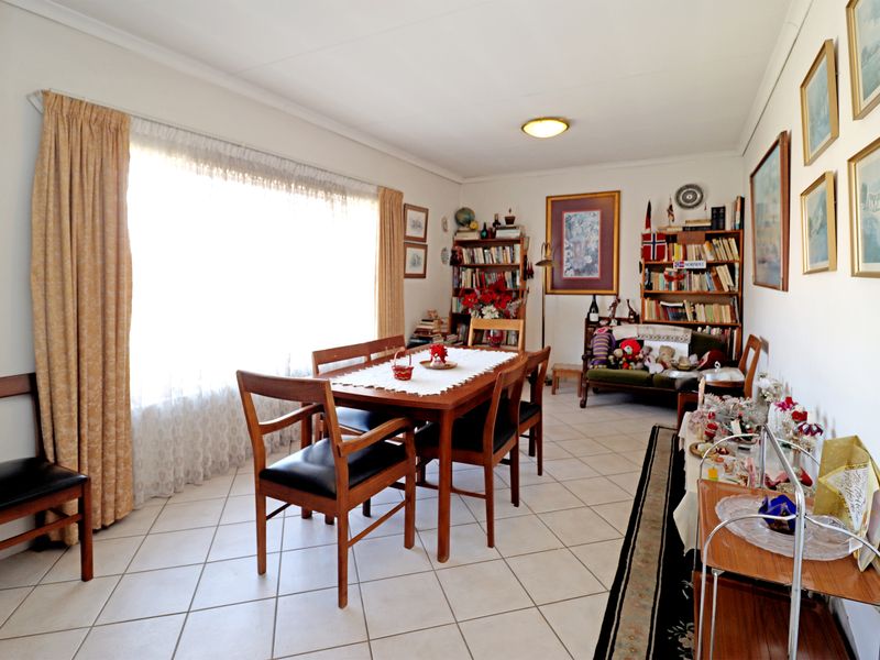 A functional dining room featuring ceramic floor tiles and a large window that provides ample natural light.