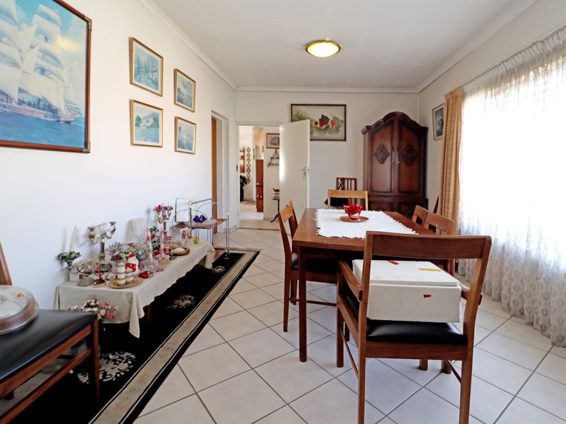 A well-lit dining room featuring neutral tiled flooring and coved cornicing, providing a functional space for family meals and entertaining.