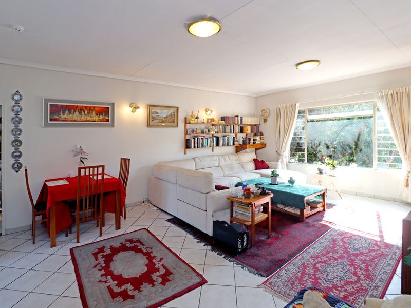 Spacious open-plan living and dining area featuring ceramic tiled flooring, large windows for natural light, and neutral wall finishes.