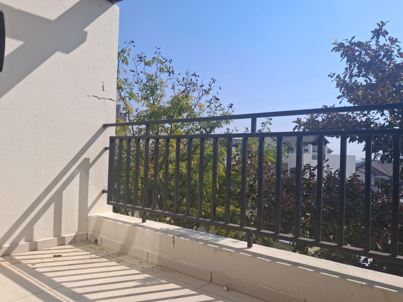 A private balcony featuring a metal balustrade and tiled flooring, showing visible signs of wall plaster cracking.