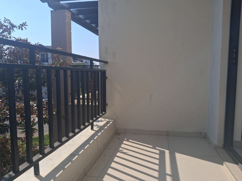 A private balcony featuring tiled flooring and a metal balustrade, offering an open outdoor space accessible via a sliding door.