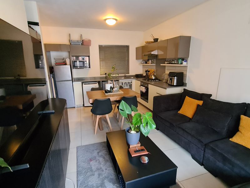 Open-plan living and kitchen area featuring modern cabinetry, integrated appliances, tiled flooring, and a functional layout suitable for contemporary apartment living.