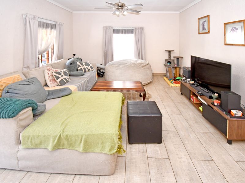 A spacious living room featuring light-toned tiled flooring and a ceiling fan, providing a neutral foundation for comfortable family living.