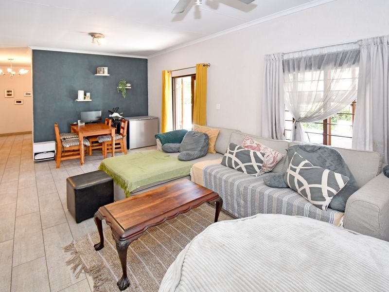 Spacious living area featuring tiled flooring, a ceiling fan, and a sliding glass door providing access to the outdoor space.
