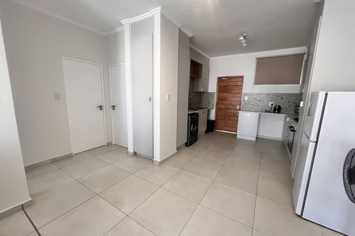 A functional kitchen featuring tiled flooring, built-in cabinetry, a stone-look backsplash, and integrated appliances, offering a clean and practical layout.