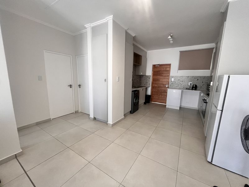A functional kitchen featuring tiled flooring, built-in cabinetry, a stone-look backsplash, and integrated appliances, offering a clean and practical layout.