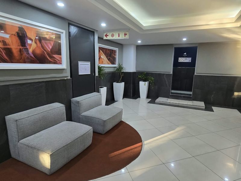 Modern apartment building lobby or clubhouse area featuring polished tile flooring, recessed cove lighting, and contemporary dark stone wall accents.
