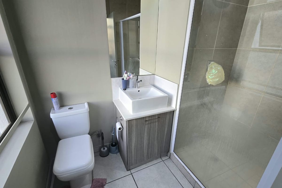 A functional bathroom featuring a modern vessel sink vanity, a white toilet, and a glass-enclosed shower with tiled flooring.