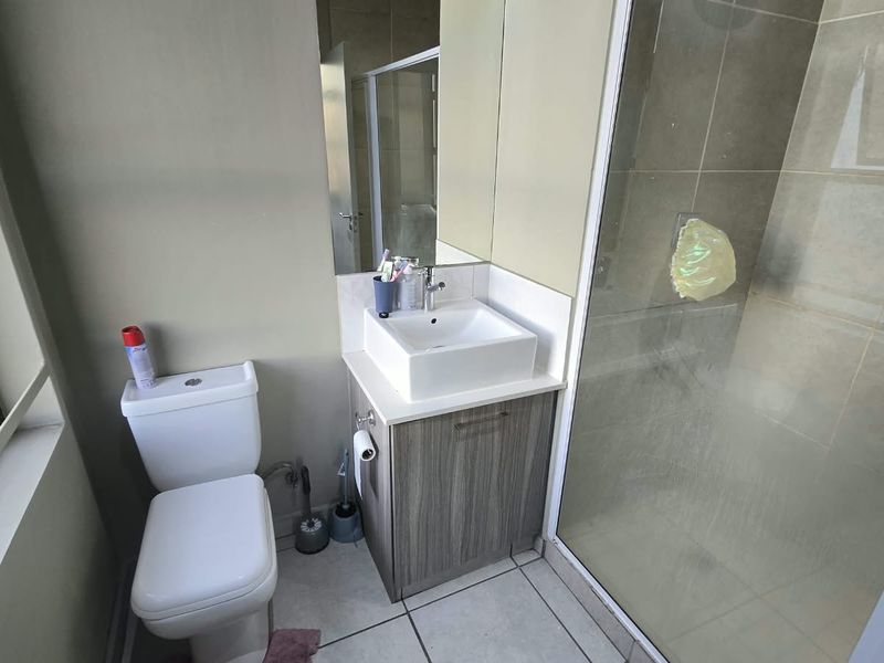 A functional bathroom featuring a modern vessel sink vanity, a white toilet, and a glass-enclosed shower with tiled flooring.