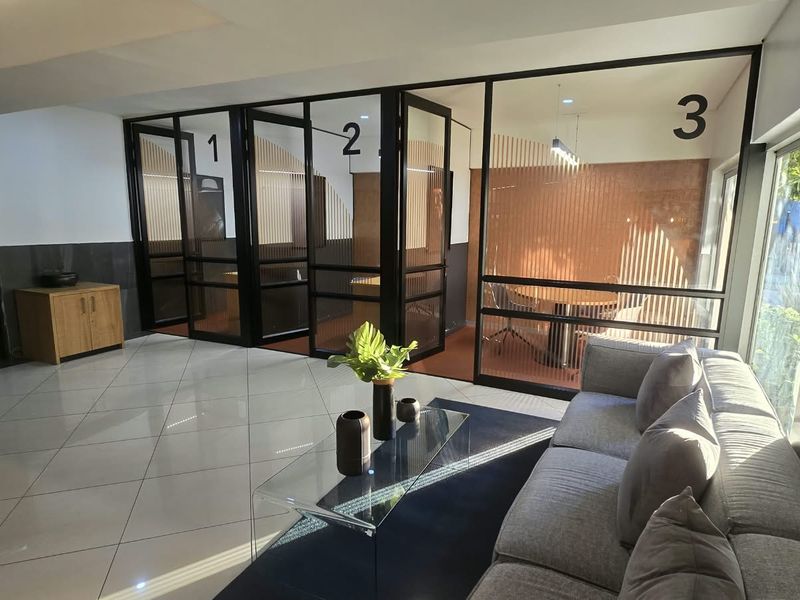 Modern office space featuring glass-partitioned meeting rooms, polished tile flooring, and a professional reception or waiting area.