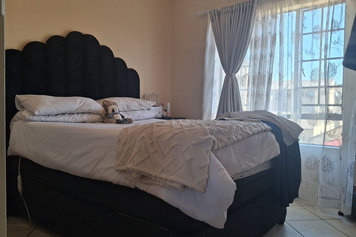 A bedroom featuring tiled flooring and a window with installed curtain tracks, providing natural light to the space.