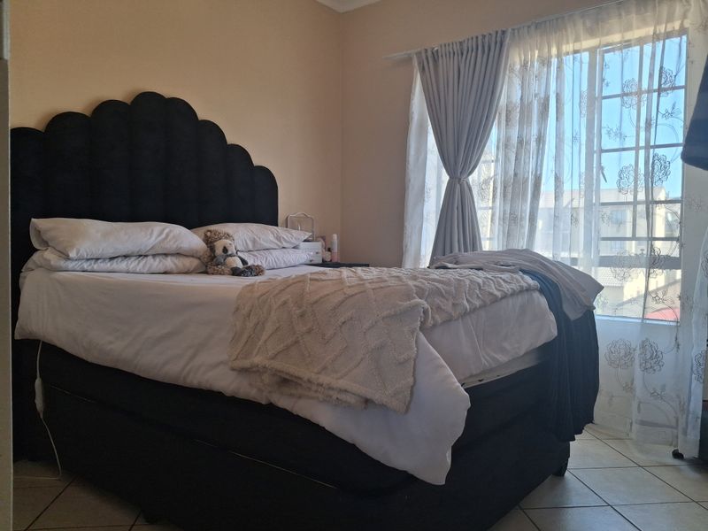 A bedroom featuring tiled flooring and a window with installed curtain tracks, providing natural light to the space.